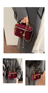 Detail of burgundy velvet quilted bag featuring gold clover logo and chain strap