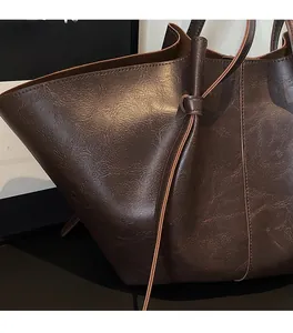Close-up of dark brown tote bag showing pleated faux leather texture and strap details