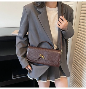 Détail du sac en cuir gaufré serpent avec boucle dorée sur une tenue élégante