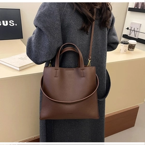 Brown litchi grain leather tote bag with dual handles and long strap shown on a model