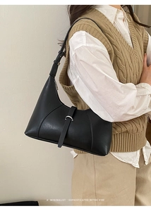 Vista laterale di una borsa a spalla minimalista nera in pelle su una modella