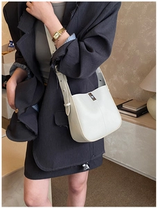 Detailed view of cream leather bucket bag featuring lychee texture and silver metal clasp