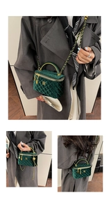 Detailed view of dark green velvet quilted vanity bag with gold clover logo and chain strap