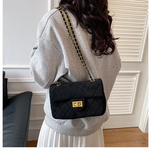 Détail d'un sac bandoulière noir matelassé avec chaîne dorée et fermoir métallique
