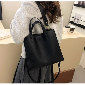 Detail of black lychee grain leather tote bag with adjustable strap on a lifestyle background
