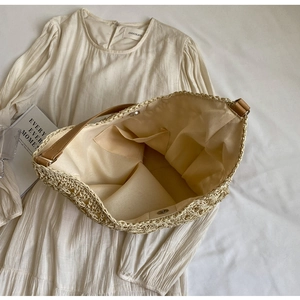 Top view of spacious straw tote bag with fabric lining and brown leather handles