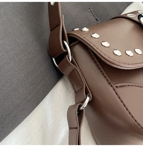 Detail view of dark brown faux leather shoulder bag with silver rivet trim and metal D-ring