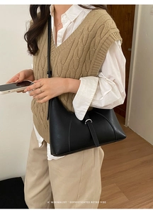Borsa hobo nera minimalista con fibbia argentata indossata da una modella stile retrò