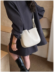 Lifestyle shot of white pebbled leather bucket bag worn as a stylish shoulder accessory