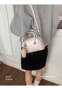 Détail du sac baguette blanc cassé avec clous sphériques argentés et breloque en peluche