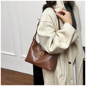 Close-up of a vintage brown leather shoulder bag with a gold round twist lock and strap