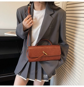 Détail d'un sac à main marron avec gaufrage serpent, fermoir doré et bandoulière