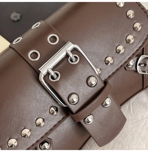 Detailed macro shot of dark brown leather handbag with silver metal rivets and buckle