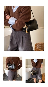 Close-up of black patent leather crossbody bag with gold studs and floral charm