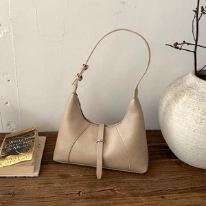 Dettaglio della borsa hobo in pelle albicocca con fibbia metallica su tavolo vintage