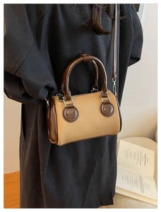 Close-up of a mini Boston bag with khaki canvas and brown patent leather details