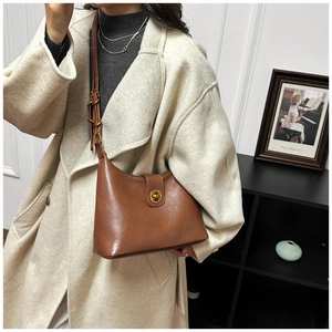 Detailed view of the vintage brown leather texture and golden metal twist lock on hobo bag