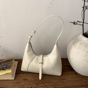 Dettaglio borsa hobo crema su tavolo in legno con cerniera e tracolla regolabile