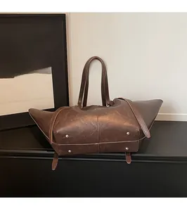 Detailed view of dark brown tote bag base featuring protective metal feet and leather texture