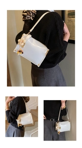 Detail of white patent leather shoulder bag with gold rivets and floral tassel charm