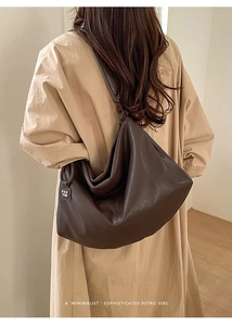 Macro shot of deep brown tote bag with metal brand tag on soft leather side