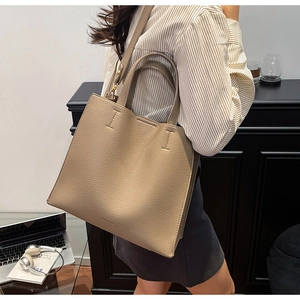 Brown lychee leather tote bag shown in a professional office setting with laptop