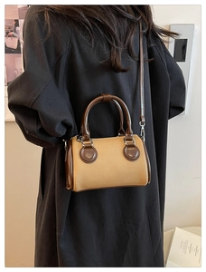 Khaki fabric Boston bag with brown leather trim shown on a black coat outfit