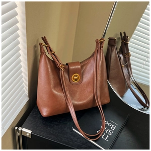 Detail of vintage dark brown faux leather bucket bag with gold circular twist-lock closure