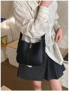 Detail of black lychee grain leather bucket bag with a silver metal clasp closure