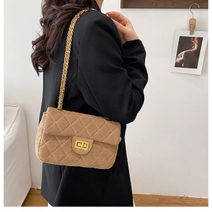 Détail du sac bandoulière matelassé en daim camel avec chaîne dorée et fermoir rotatif