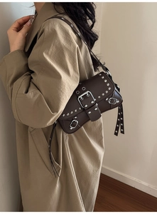 Detail of dark brown leather bag featuring silver metal rivets and a large buckle strap