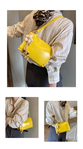 Detail of yellow crossbody bag with gold rivets and floral tassel charm for women