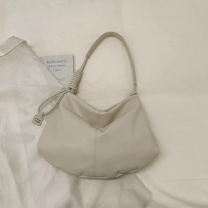 Close-up of a cream hobo bag with knotted strap detail and metal logo tag
