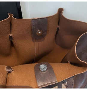 Detail of magnetic closure and textured faux suede lining on a dark brown tote bag