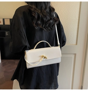 Détail du sac bandoulière blanc à motif animalier et boucle dorée à nœud