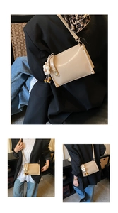 Detail of a beige minimalist crossbody bag with floral bead charm and metal rivets
