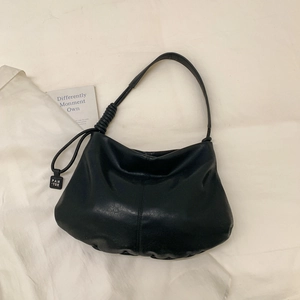 Detail of minimalist black soft leather tote bag with stylish knot strap and logo tag