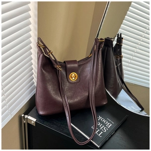 Detail of burgundy leather handbag featuring a vintage gold twist lock and smooth texture