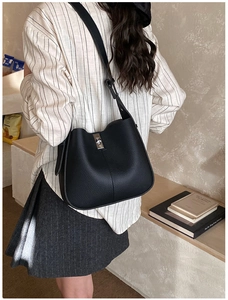 Close-up of black litchi pattern bucket bag with silver metal lock on a model back