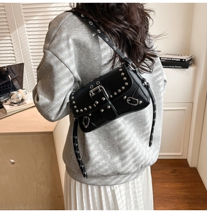 Detail of a black punk PU leather shoulder bag with silver studs and metal buckle detail