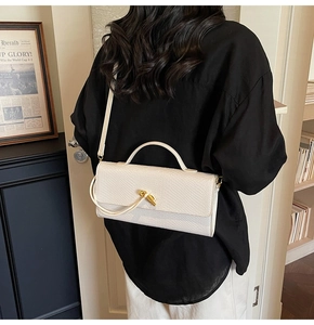 Détail d'un sac à bandoulière blanc motif crocodile avec fermoir rotatif doré chic