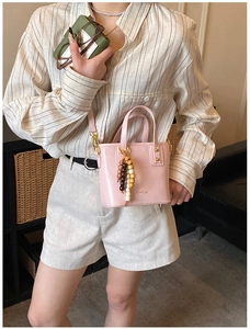 Détail du sac seau rose brillant avec pompon en perles et bandoulière fine