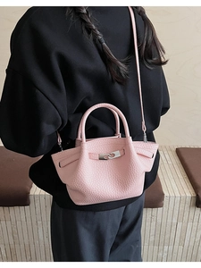 Close-up of pink pebbled leather bucket bag with metal buckle and detachable strap