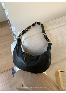 Détail du sac hobo noir avec bandoulière chaîne dorée sur un fond minimaliste et doux