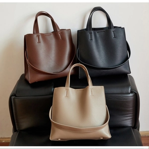 Detailed view of three pebbled leather tote bags in brown, black, and beige colors