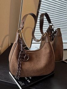 Brown suede hobo shoulder bag on magazine with elegant golden metal ring accents