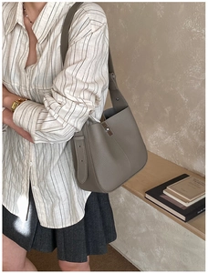 Detailed view of taupe bucket bag in lychee pattern leather with silver clasp and wide strap