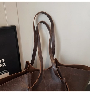 Close-up of brown faux leather tote bag showing detailed lychee grain texture and dual straps