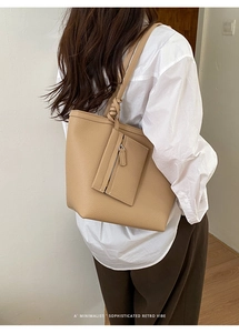Khaki pebbled leather tote bag with small pouch shown on shoulder in lifestyle setting