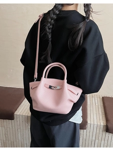 Close-up of pink lychee leather bucket bag with silver metal buckle and folded side design